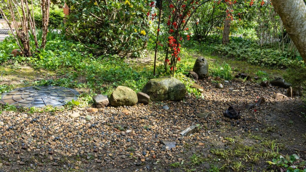 Septic access hatch disguised with stonework in a garden