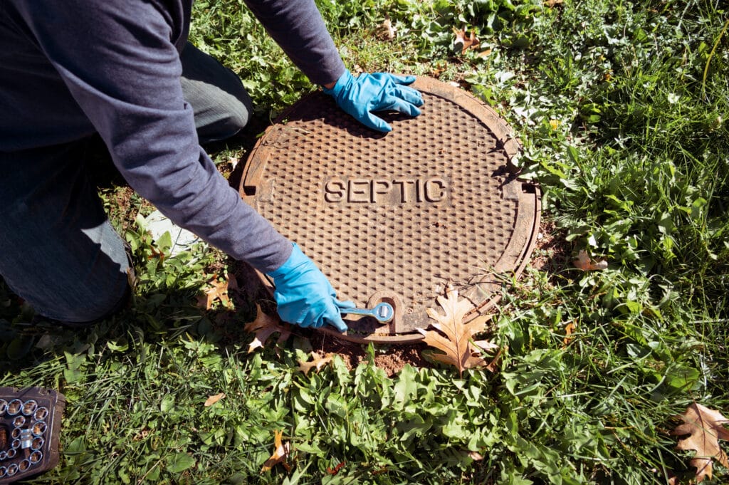 A working plumber opening septic system tank. Copy space for tex